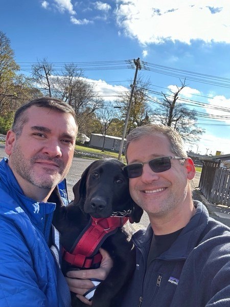 Two people standing together with one holding a dog.