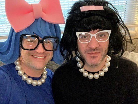 Two people wearing wigs and glasses.