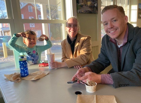 A person and person sitting at a table with a child.