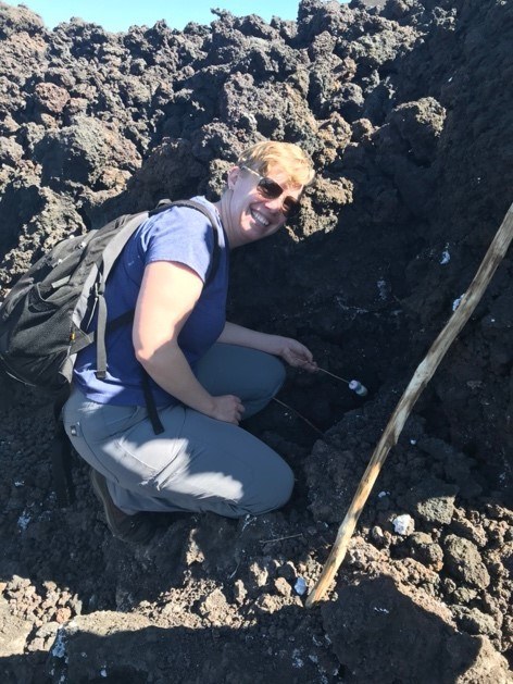 A person sitting in a rocky area holding marshmallows.