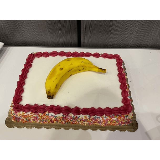 A cake with a realistic banana made of icing.