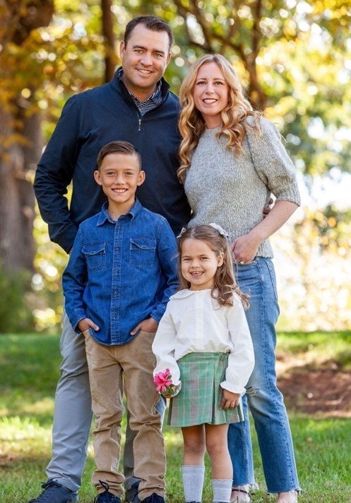 Ashley, her husband, and their two young children posing together for a family photo.