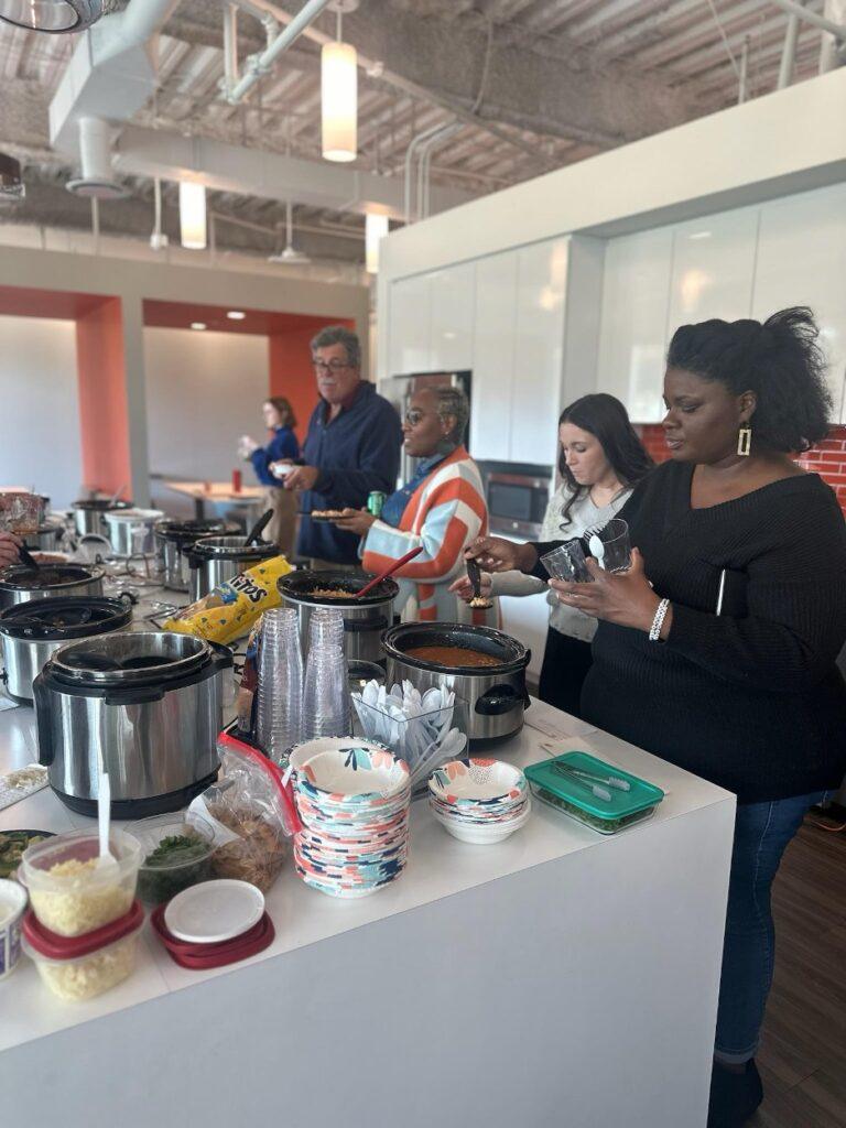 4 FMP employees in a kitchen preparing food and eating.