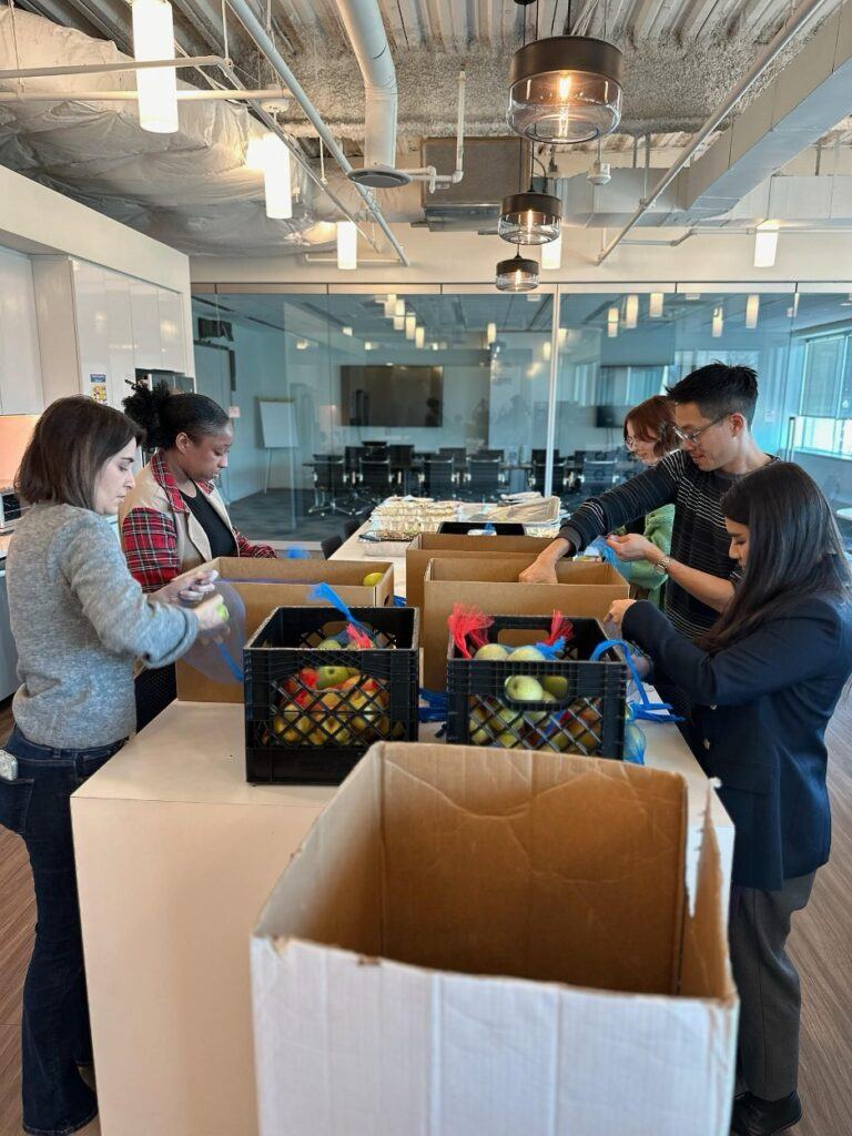 5 FMP employees in an office setting packing boxes of food.