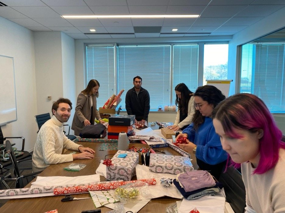 6 FMP employees in a conference room, wrapping gifts.